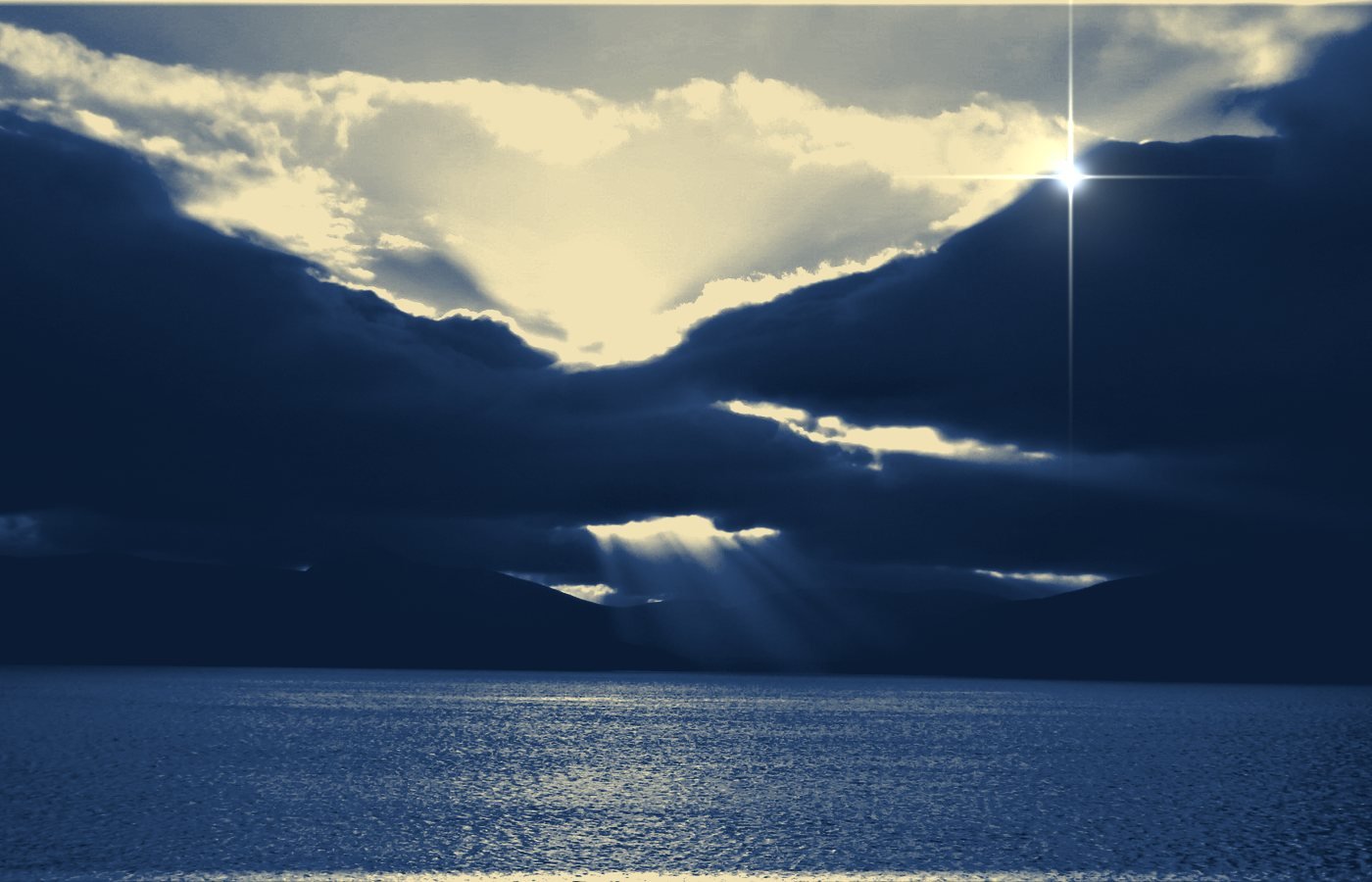 Sunlight breaking through dark clouds over water — the fresh start