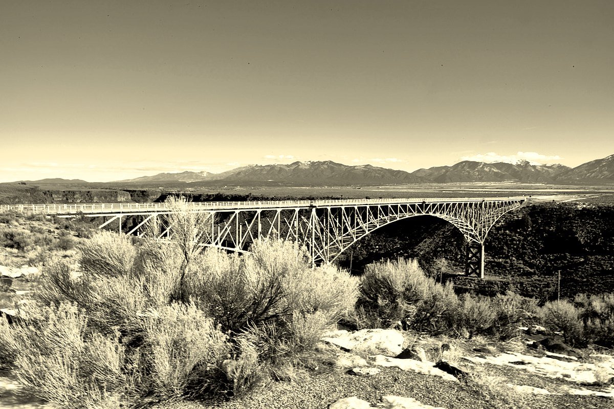 The steel arch bridge spanning the Rio Grande Gorge near Taos, New Mexico, with mountains behind