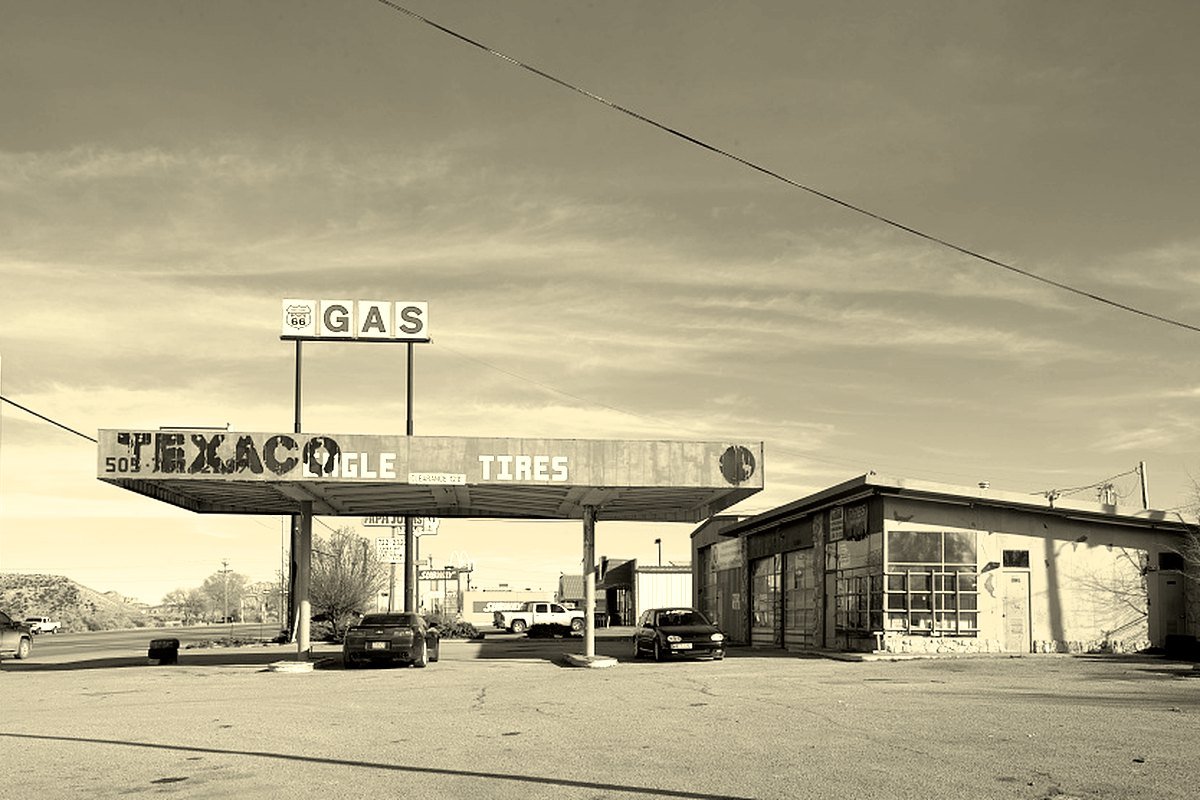 A closed roadside gas station and tire shop under a wide canopy on old U.S. Route 66 in Gallup, New Mexico